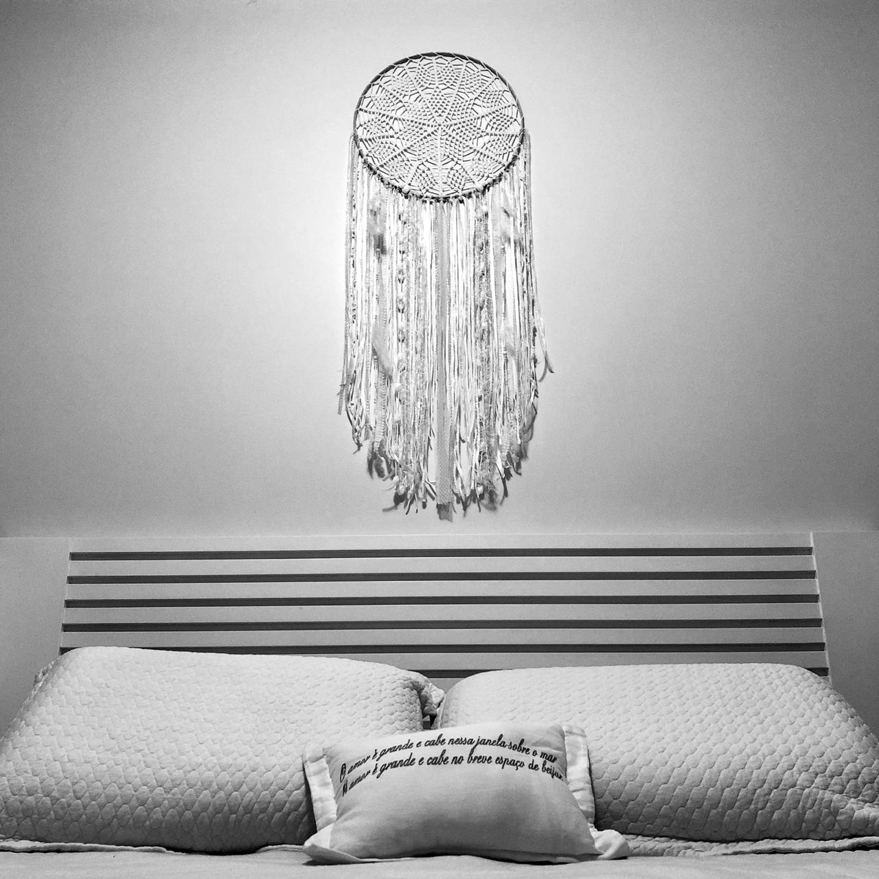 quarto branco com decoração de filtro dos sonhos na cabeceira da cama